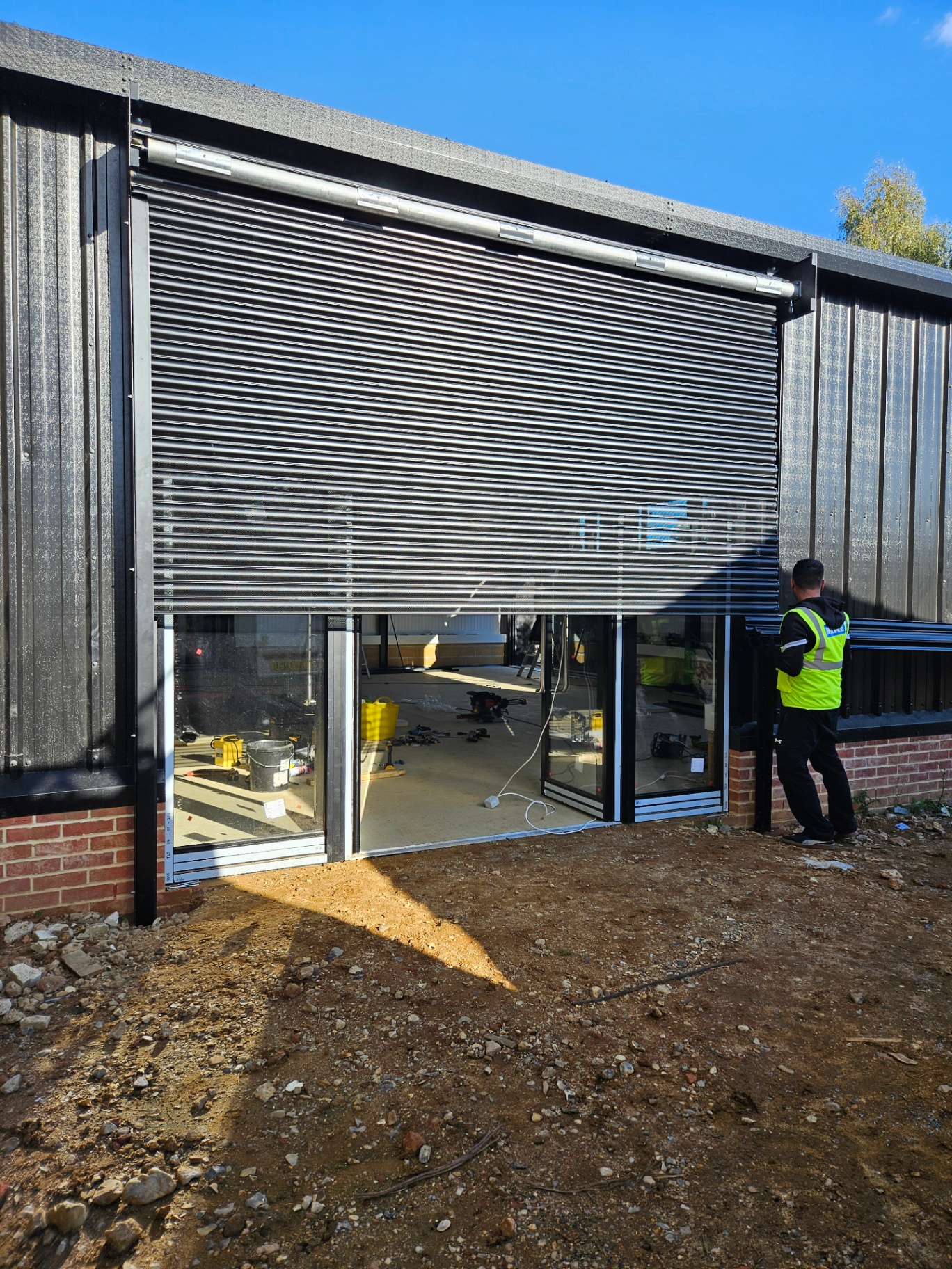 Commercial roller shutter installation on a black aluminium façade – Prestige Aluminium Systems